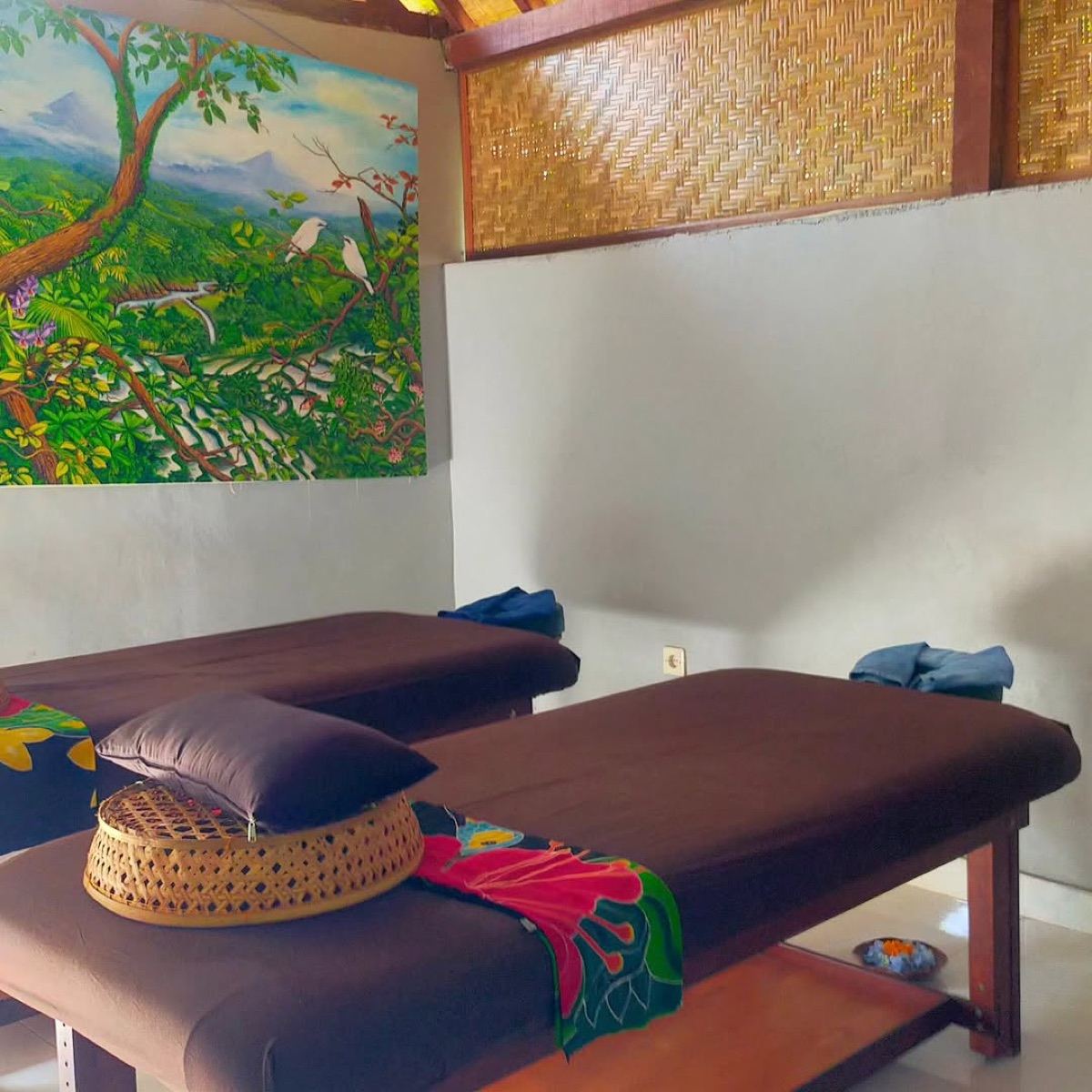 Two massage beds and Balinese painting in the treatment room at Rina Massage, Ubud